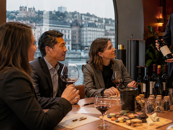 Groupe de collaborateurs participant à une dégustation de vin animée par un sommelier.